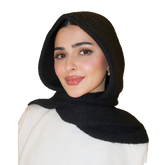Woman wearing a black headscarf and white top on a white background