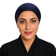 A woman wearing a navy blue ribbed knit hijab and a black garment, shown from the chest up against a plain white background.