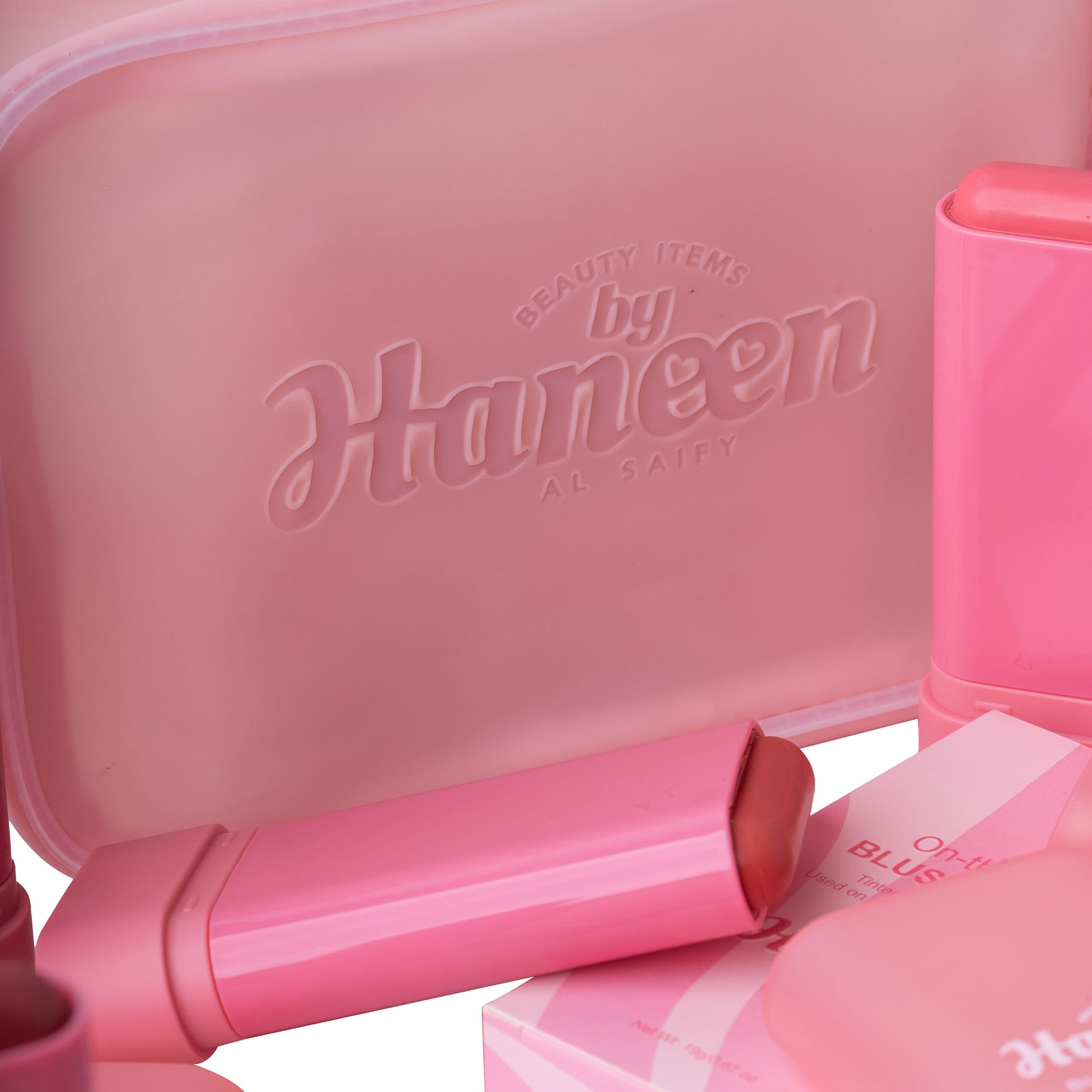 Pink makeup case with 'Haneen' branding and various pink makeup items.