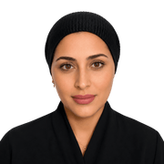 A woman wearing a black ribbed knit hijab and a black collared garment, photographed against a solid black background.