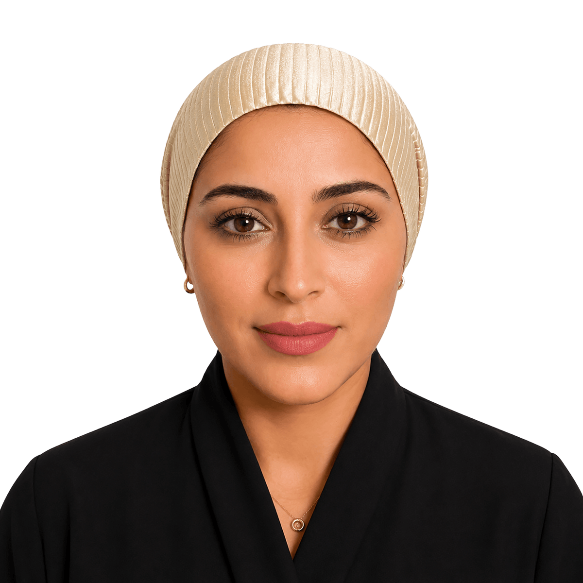 A woman wearing a cream-colored pleated hijab and a black collared garment, photographed against a solid black background.