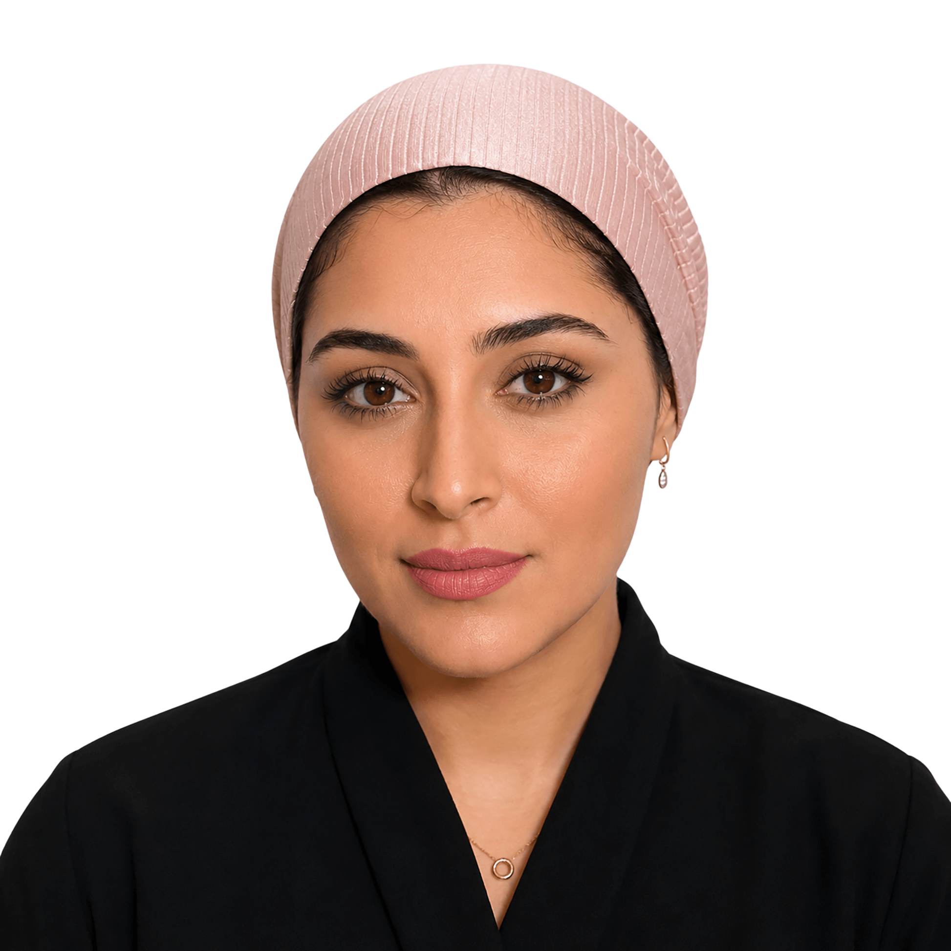 A woman wearing a light pink pleated head covering and a black abaya, shown from the chest up against a plain white background.