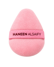 A pink teardrop-shaped makeup sponge with a matching pink band around the middle that reads 'HANEEN ALSAIFY' in black text, shown on a plain white background.
