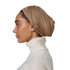 Woman wearing a beige headscarf and white turtleneck on a white background