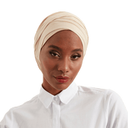 Woman wearing a beige headscarf and white shirt on a white background