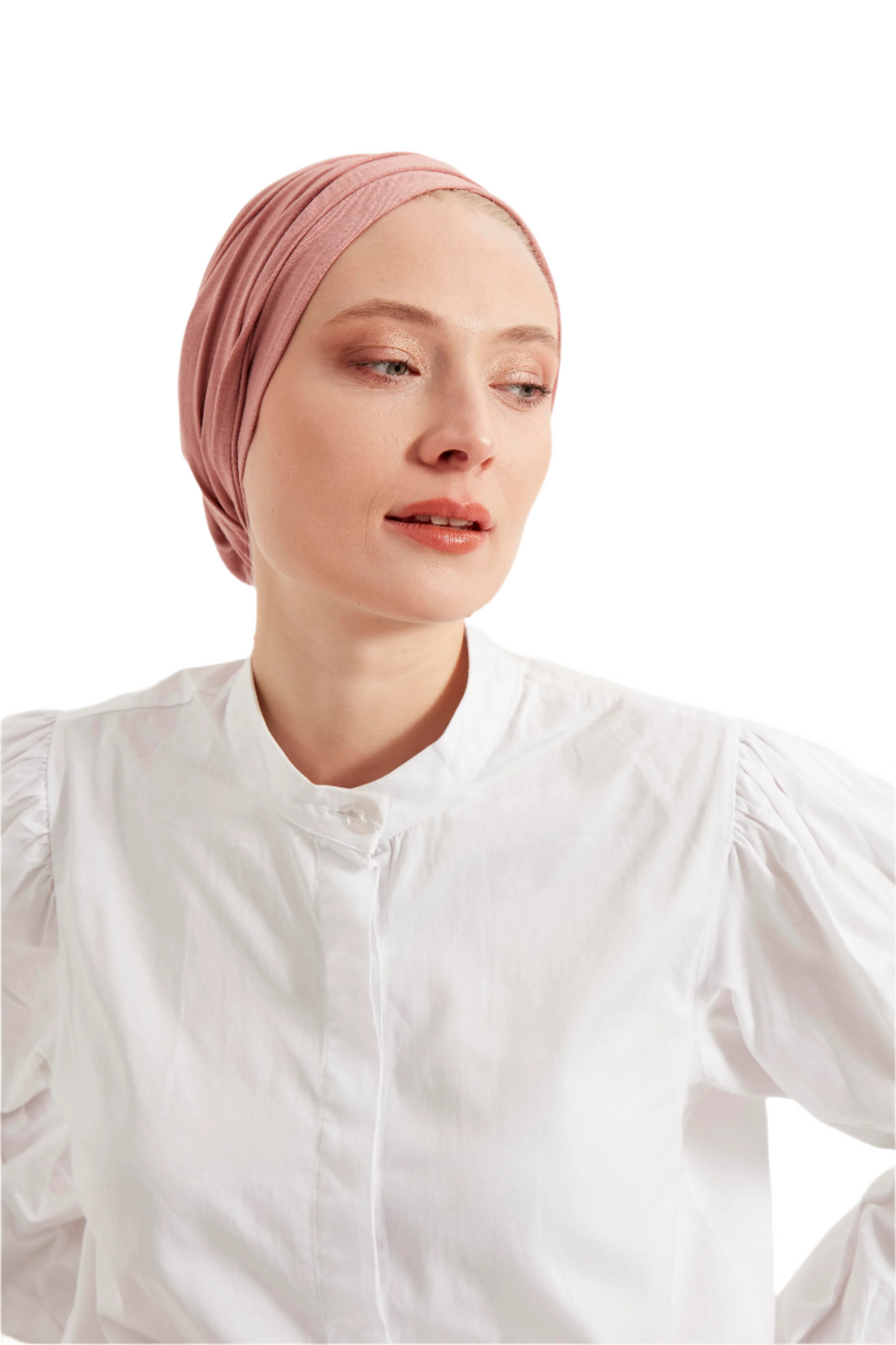 Woman wearing a pink headscarf and white shirt against a light background