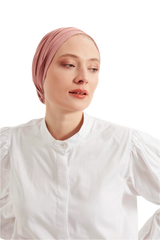 Woman wearing a pink headscarf and white shirt against a light background